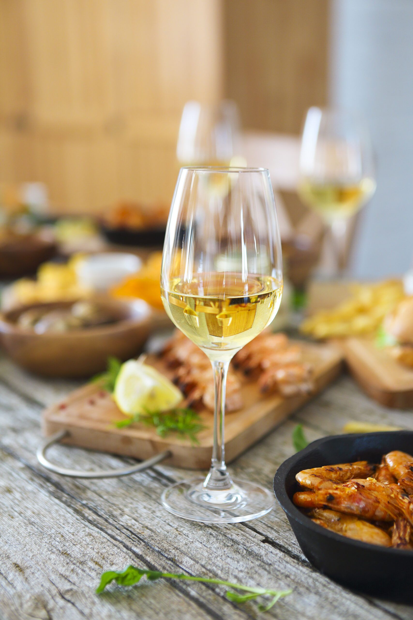 Una mesa de cocina llena de comida y una copa de vino blanco