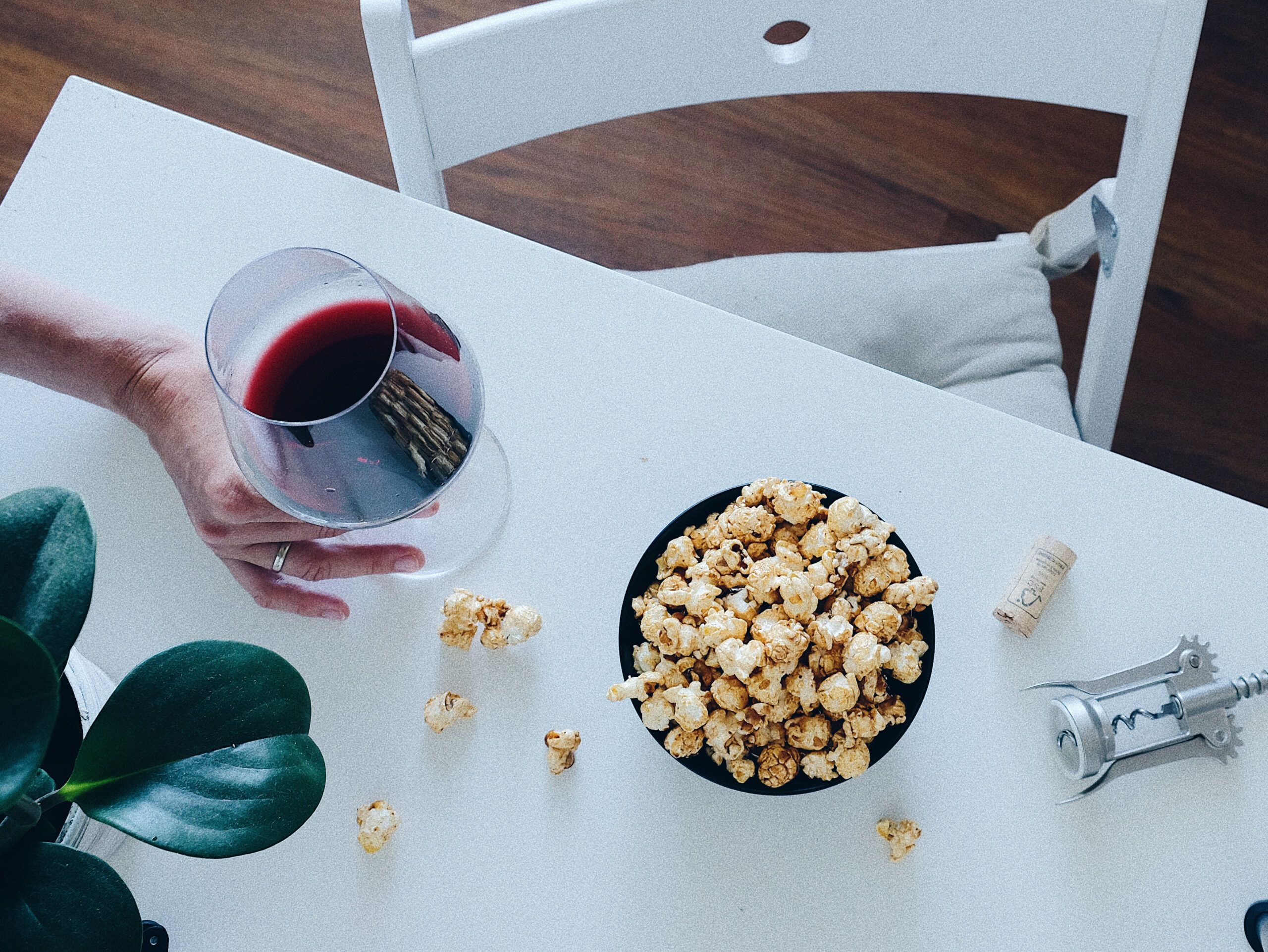 Una copa de vino sobre la mesa con un bol de palomitas. Un plan para una tarde de invierno en casa.