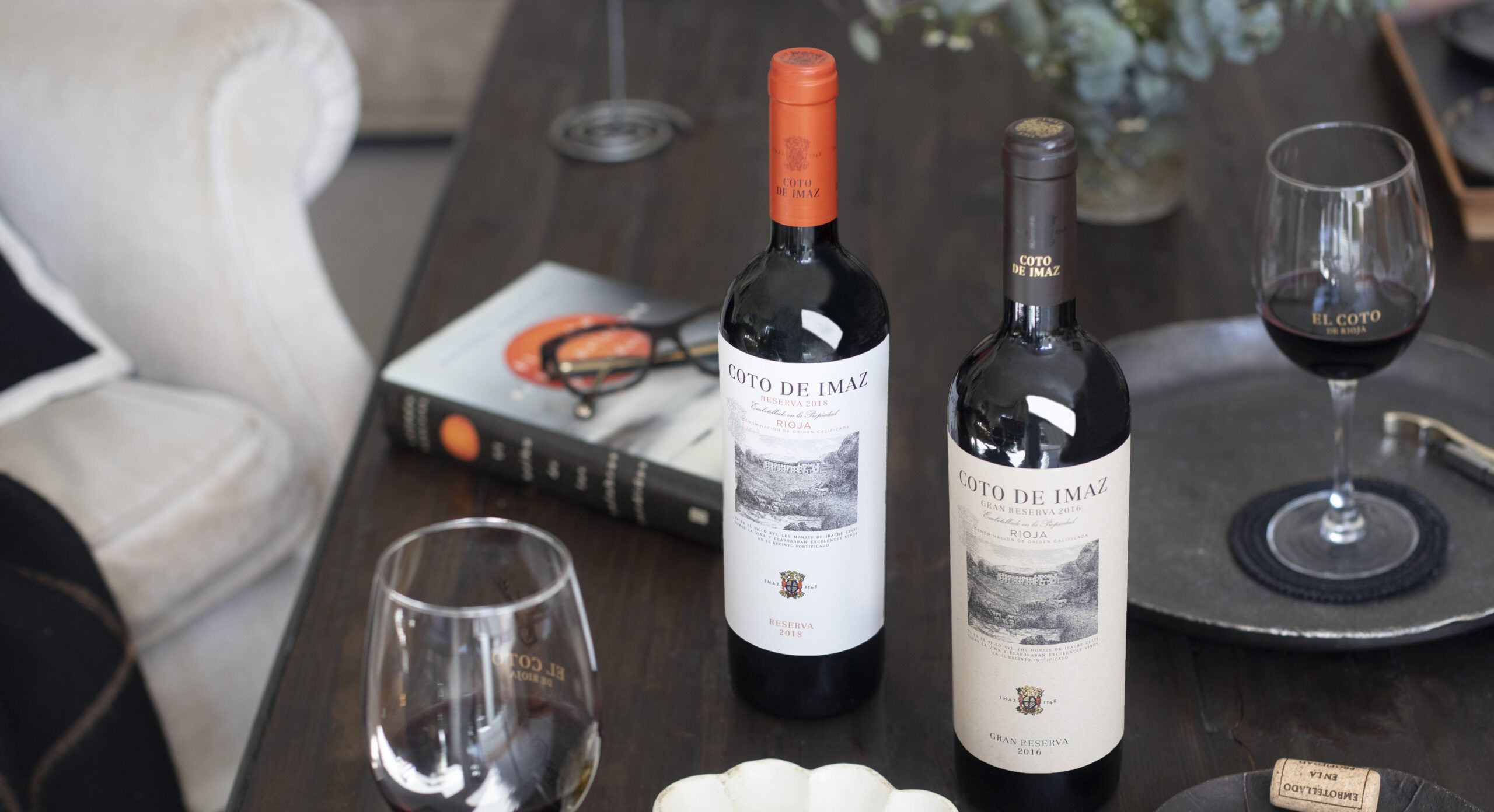 Cotod e Imaz Reserva y Gran Reserva sobre una mesa con copas de vino y un libro